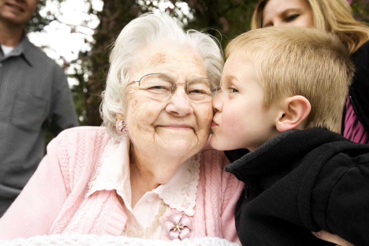 Ett barn pussar sin mormor eller farmor på kinden.